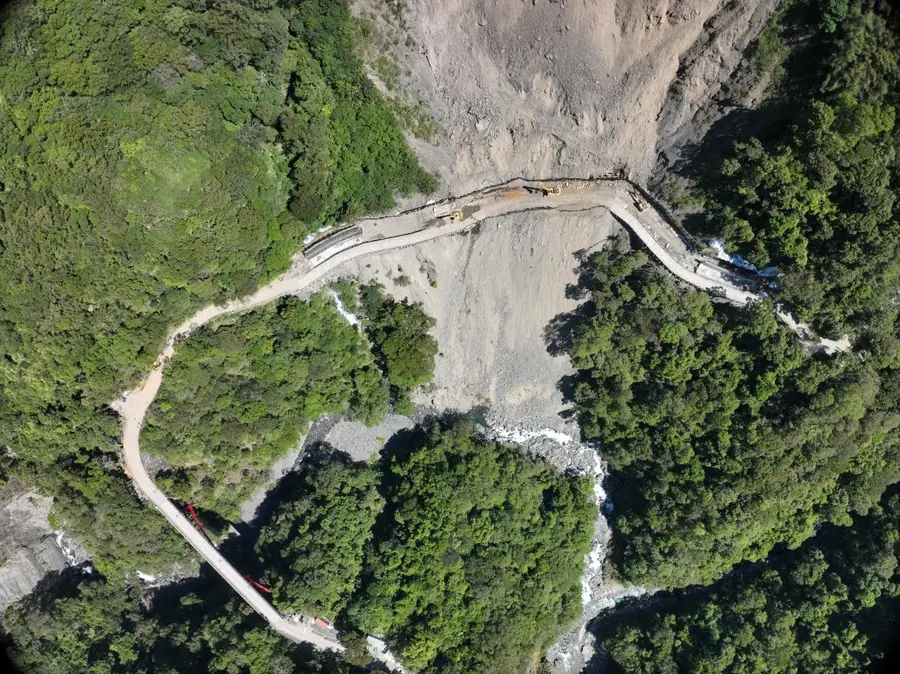 Aerial view of a landslide, road, and channel in a mountain catchment